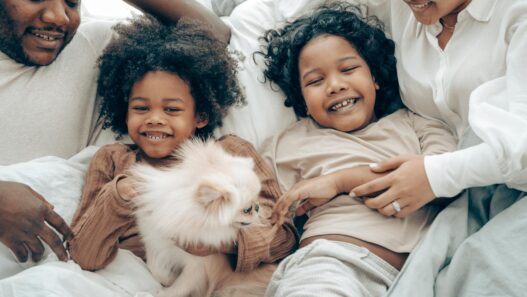 Happy family bonding time with kids and a Pomeranian dog in cozy home setting.