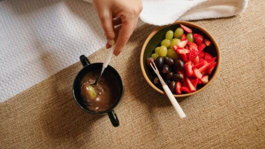 Top view of a delicious fruit and chocolate fondue setup with strawberries, grapes, and dipping cup.