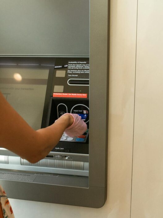 Woman using an ATM machine while wearing protective gloves indoors.