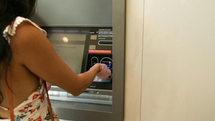 Woman using an ATM machine while wearing protective gloves indoors.