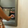 Woman using an ATM machine while wearing protective gloves indoors.