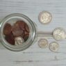 Top view of a jar filled with coins placed on a wooden table, depicting savings.