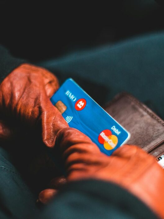 Close-up of hands in gloves holding a credit card and wallet indoors.