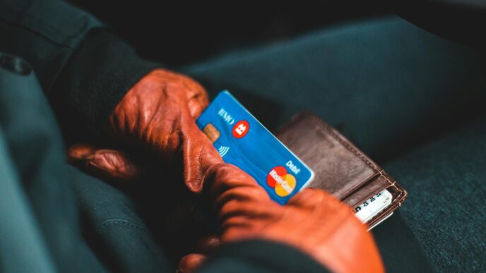Close-up of hands in gloves holding a credit card and wallet indoors.