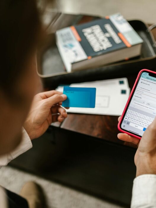 Person making an online payment using a smartphone and credit card indoors.