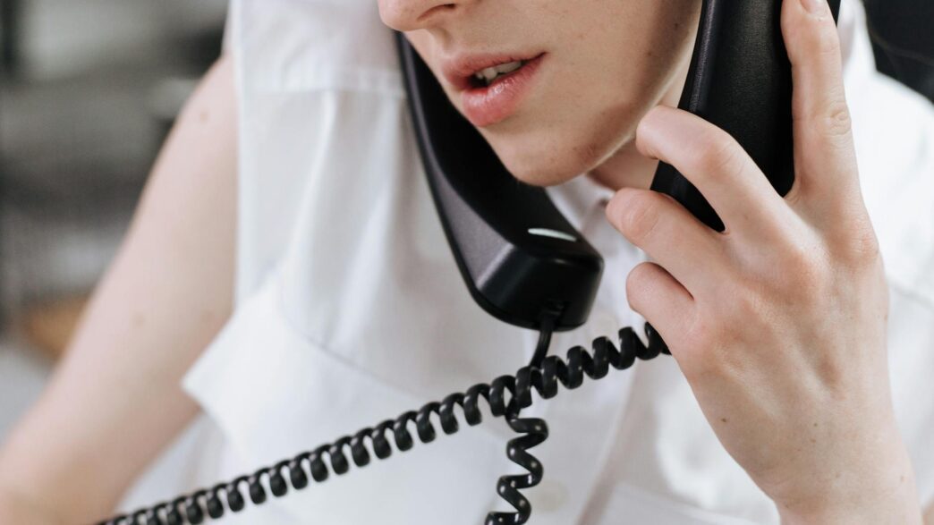 Person on a phone call reviewing a paper bill at a desk, illustrating negotiating lower monthly bills
