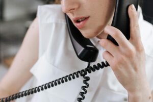 Person on a phone call reviewing a paper bill at a desk, illustrating negotiating lower monthly bills