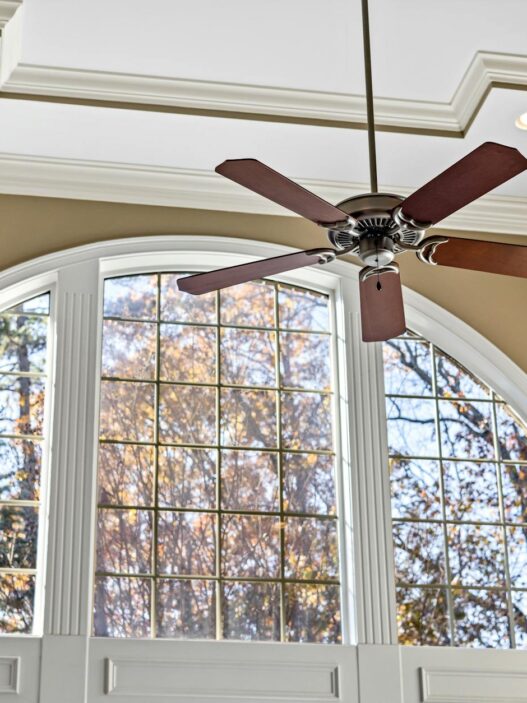 A bright living room with a ceiling fan and natural light, illustrating practical ways to lower summer cooling and energy costs.
