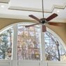 A bright living room with a ceiling fan and natural light, illustrating practical ways to lower summer cooling and energy costs.