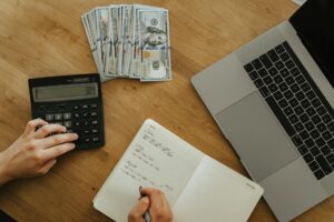 Notebook, calculator, and coffee on a desk during a mid-year personal finance review