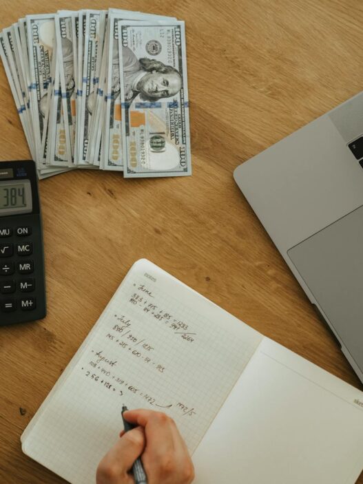 Notebook, calculator, and coffee on a desk during a mid-year personal finance review
