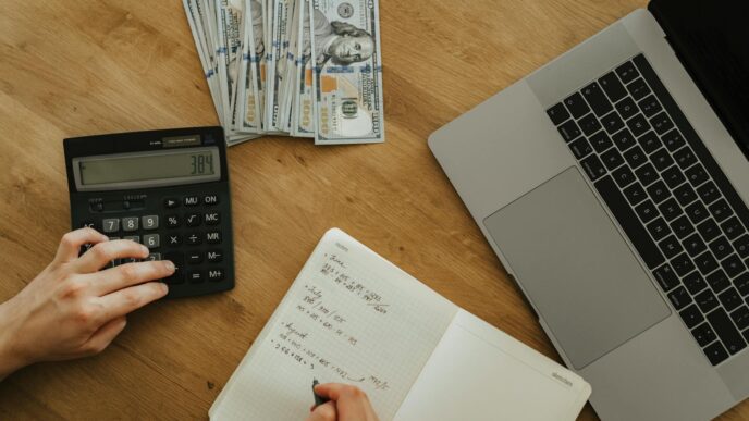 Notebook, calculator, and coffee on a desk during a mid-year personal finance review
