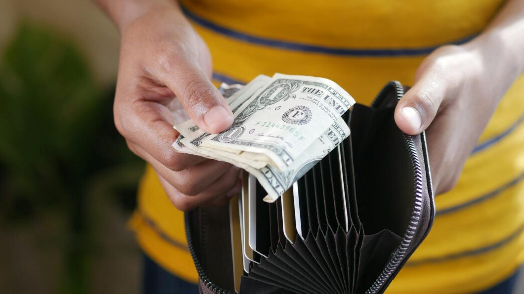 A wallet next to coins and a notebook representing a no-spend savings challenge