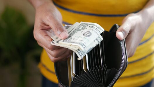 A wallet next to coins and a notebook representing a no-spend savings challenge
