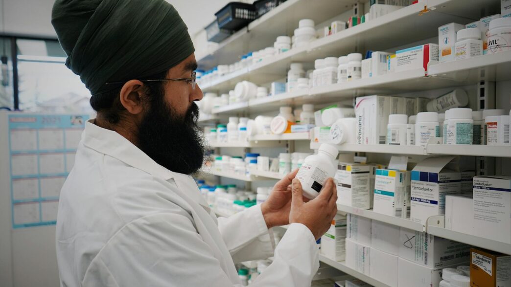 Pharmacist handing a prescription bag across a pharmacy counter, illustrating prescription drug savings