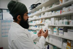 Pharmacist handing a prescription bag across a pharmacy counter, illustrating prescription drug savings