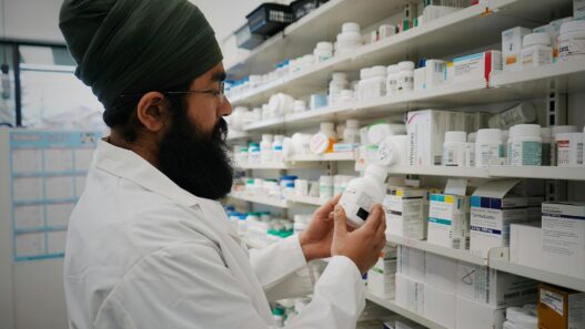 Pharmacist handing a prescription bag across a pharmacy counter, illustrating prescription drug savings