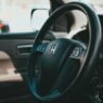 Car keys resting on a contract and steering wheel, illustrating the decision to refinance an auto loan in 2026