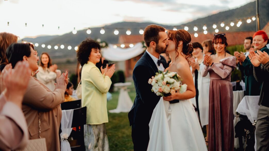 Guests celebrating at an outdoor summer wedding reception, illustrating how to attend weddings on a budget