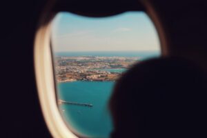 View of an airplane wing over clouds, illustrating how to find cheap summer flights in 2026