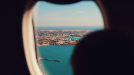 View of an airplane wing over clouds, illustrating how to find cheap summer flights in 2026