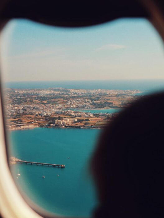 View of an airplane wing over clouds, illustrating how to find cheap summer flights in 2026