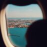 View of an airplane wing over clouds, illustrating how to find cheap summer flights in 2026