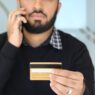 Person on the phone holding a credit card while negotiating a lower interest rate