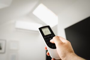 Hand adjusting a home thermostat to cut summer air conditioning costs