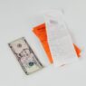 A shopper holding a receipt at a store checkout, illustrating how to request a price adjustment refund when a price drops