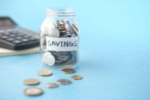 Glass jars of coins labeled for savings goals, illustrating how to set up sinking funds and savings buckets.