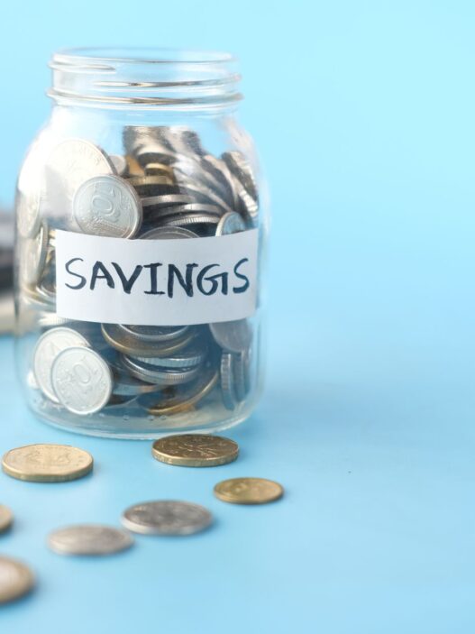 Glass jars of coins labeled for savings goals, illustrating how to set up sinking funds and savings buckets.