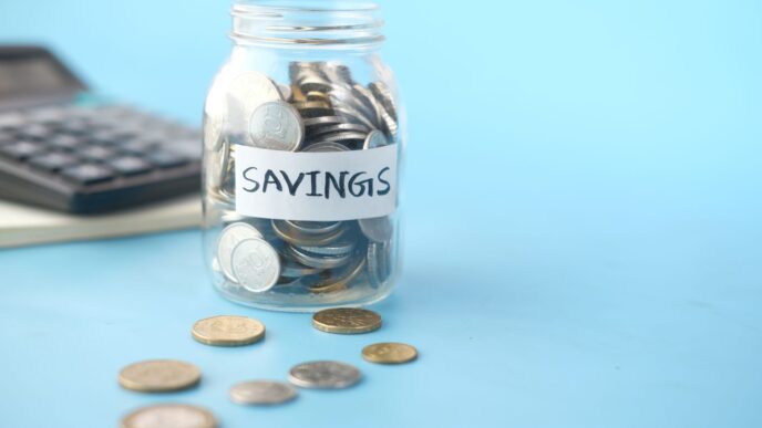 Glass jars of coins labeled for savings goals, illustrating how to set up sinking funds and savings buckets.