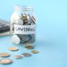 Glass jars of coins labeled for savings goals, illustrating how to set up sinking funds and savings buckets.