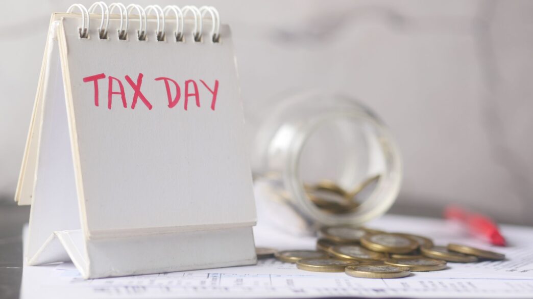Coins in a savings jar beside a calendar, illustrating how to automate savings on payday in 2026