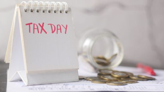 Coins in a savings jar beside a calendar, illustrating how to automate savings on payday in 2026