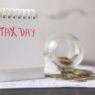Coins in a savings jar beside a calendar, illustrating how to automate savings on payday in 2026