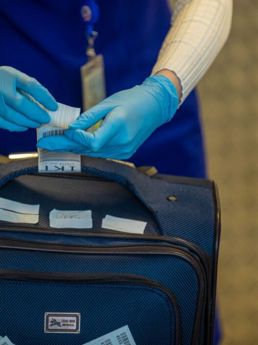 A traveler with luggage at an airport check-in counter, illustrating how to avoid airline baggage fees in 2026