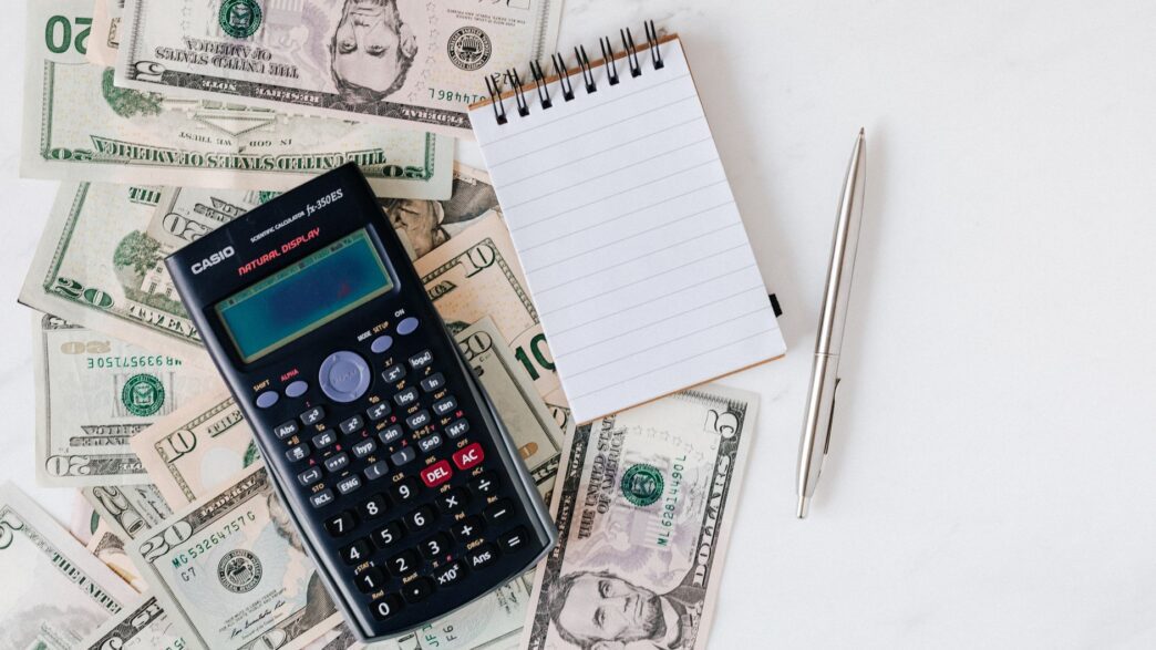 Bank statements and a calculator on a desk, illustrating how to spot and cancel unnecessary bank add-on fees