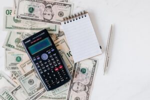 Bank statements and a calculator on a desk, illustrating how to spot and cancel unnecessary bank add-on fees