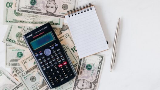 Bank statements and a calculator on a desk, illustrating how to spot and cancel unnecessary bank add-on fees