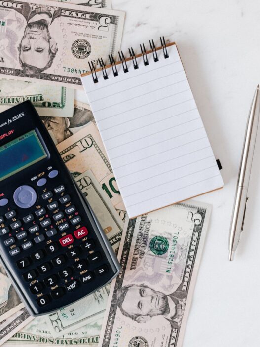Bank statements and a calculator on a desk, illustrating how to spot and cancel unnecessary bank add-on fees