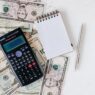 Bank statements and a calculator on a desk, illustrating how to spot and cancel unnecessary bank add-on fees