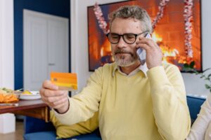 Person on a phone call holding a credit card at a desk