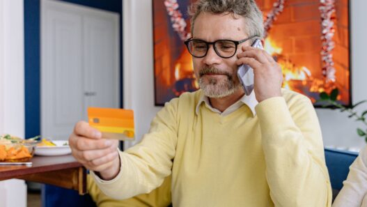 Person on a phone call holding a credit card at a desk