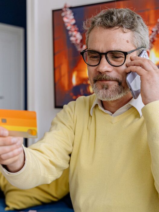 Person on a phone call holding a credit card at a desk