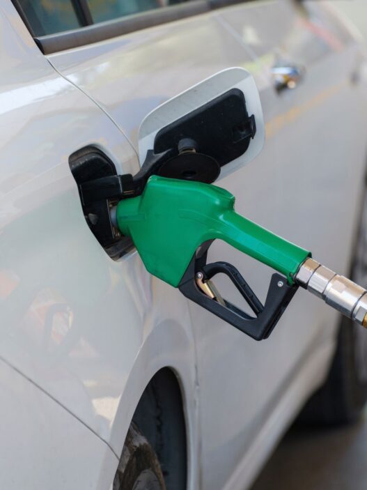 A car being refueled at a gas station pump, representing grocery fuel rewards savings