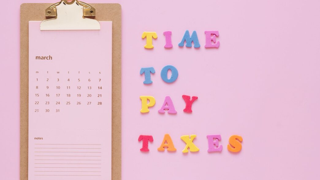 Person planning monthly bills on a calendar with a notebook and calculator