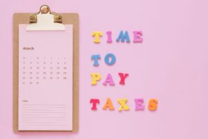 Person planning monthly bills on a calendar with a notebook and calculator