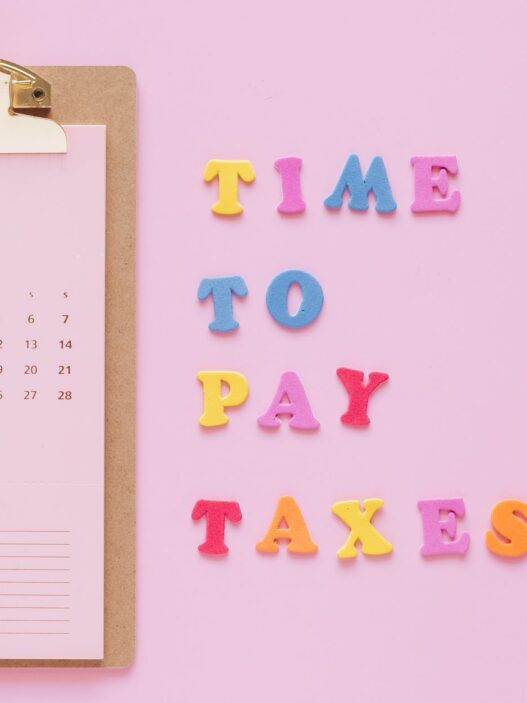 Person planning monthly bills on a calendar with a notebook and calculator
